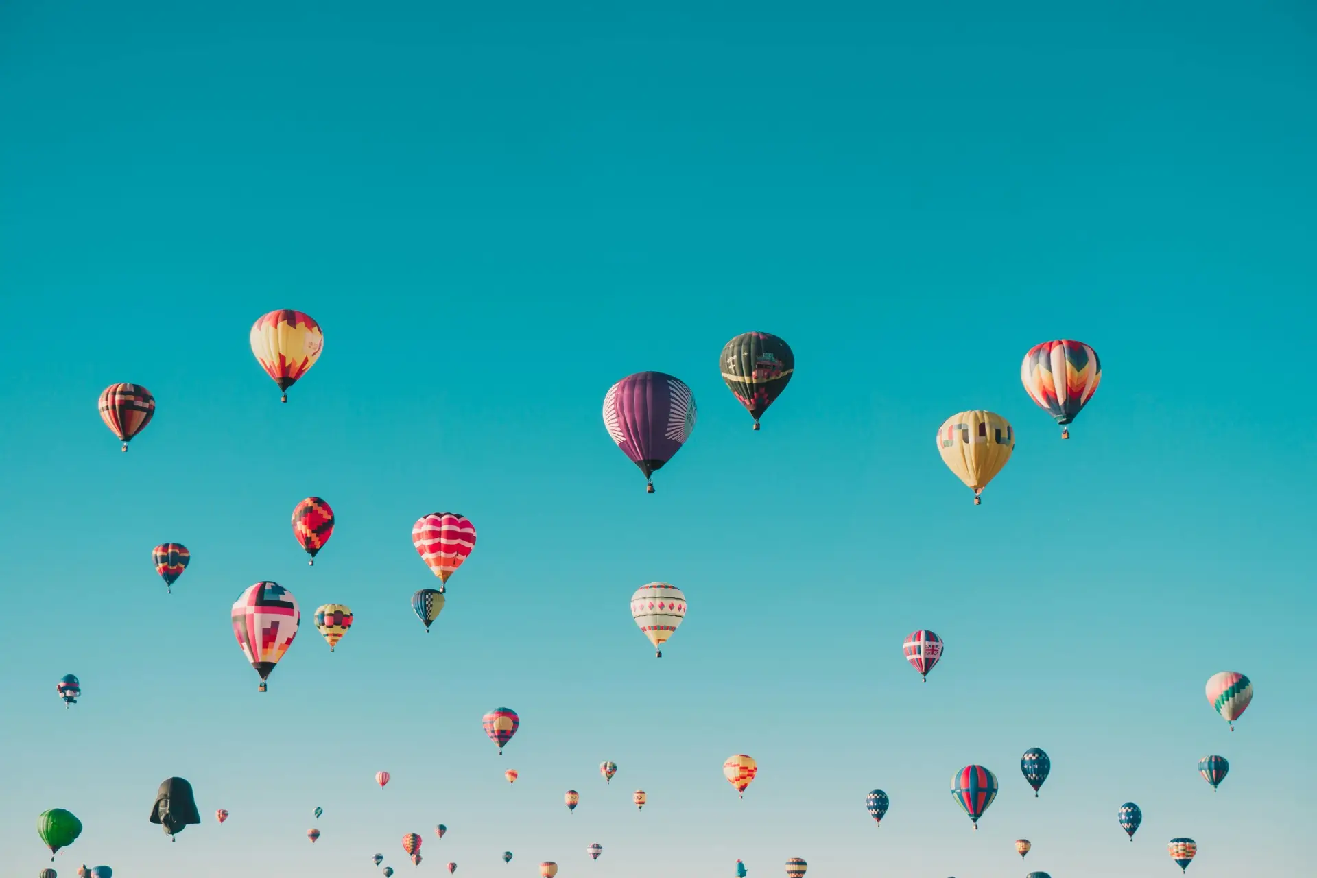 Farverige luftballoner stiger til vejrs mod en klar himmel